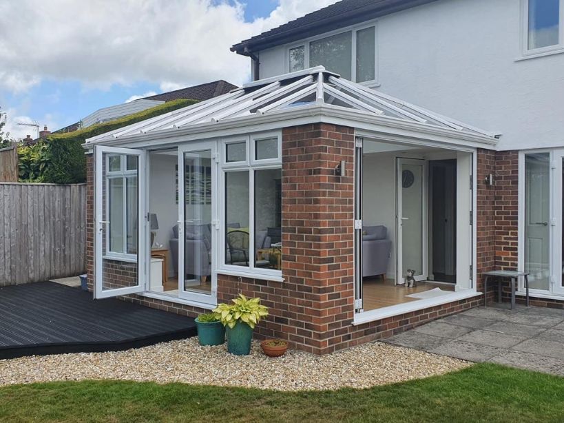 Conservatory on the back of a house in Somerset with white windows and black decking in the garden