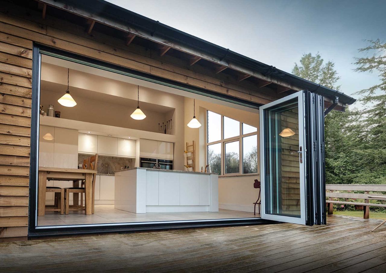 Aluminium bi-fold doors folded from modern kitchen to wooden patio